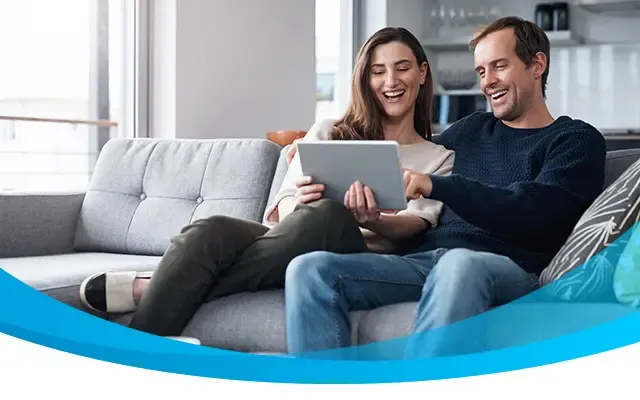 couple sitting on the sofa together and using a tablet